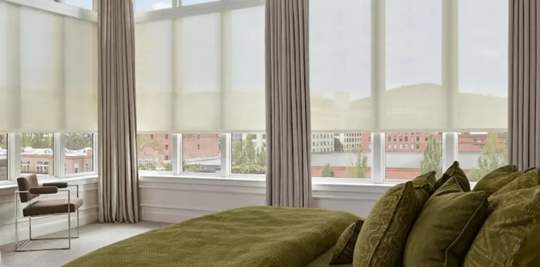 Elegant bedroom featuring large windows with city view, green bedding, and minimalist furniture.