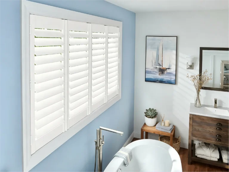 Contemporary bathroom featuring white shutters on a window, blue walls, a bathtub, and wooden cabinetry with decor items.