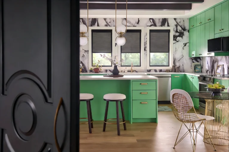 Contemporary kitchen featuring bright green cabinets, marble wall accents, and modern light fixtures. Central island with stools.