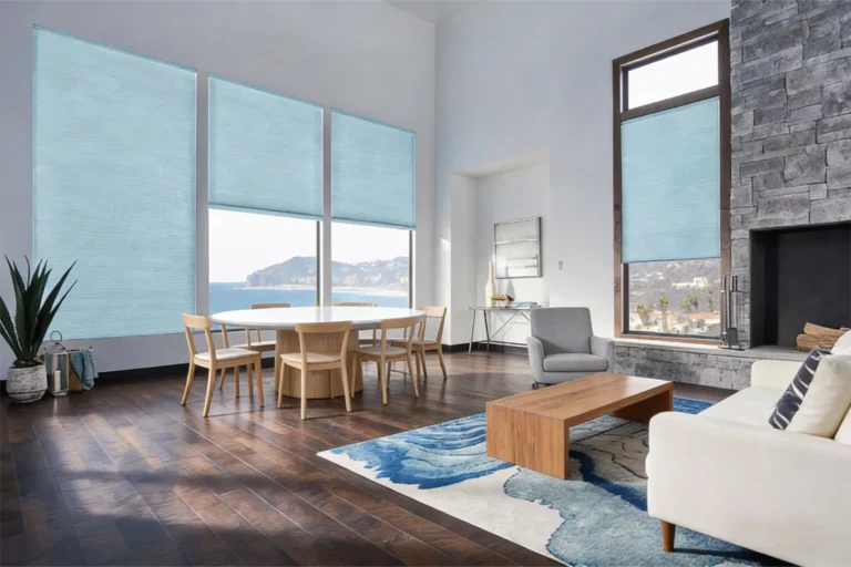 Modern living room featuring large windows with blue shades, ocean view, wooden flooring, and contemporary furniture.