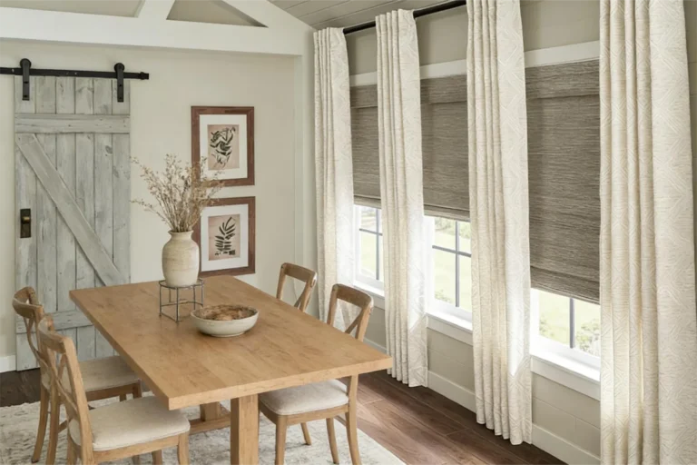 Dining room featuring a wooden table and chairs, rustic barn door, window shades, and framed botanical art.