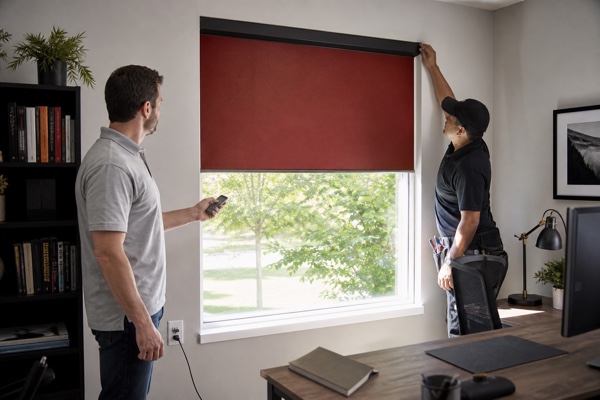 Homeowner and installer confirming a rust-red motorized roller shade