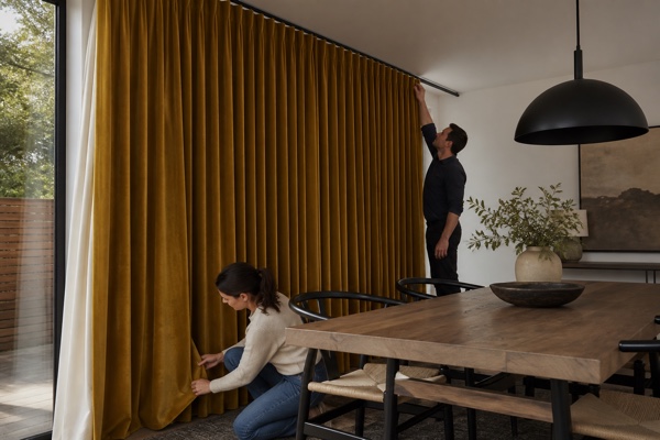 Homeowner and installer checking finished ochre custom curtains in a dining room
