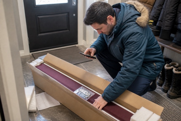Customer inspecting a delivered custom blind and package label in a Canadian home