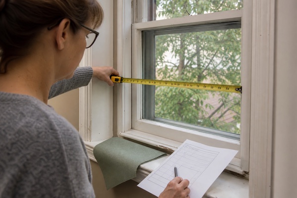 Homeowner measuring an older window opening for a custom shade