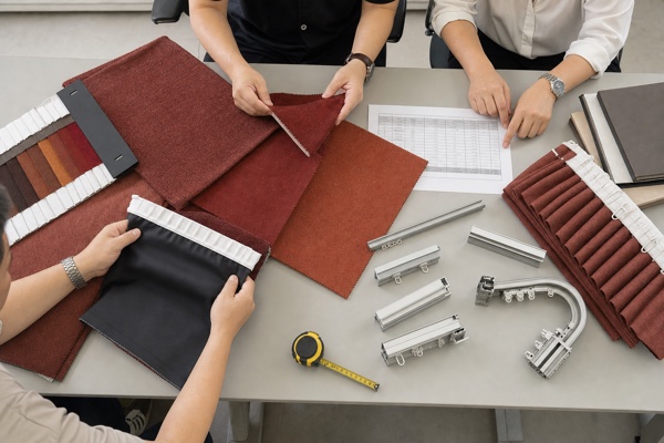A project team compares terracotta curtain fabrics, blackout lining, headers, and track samples